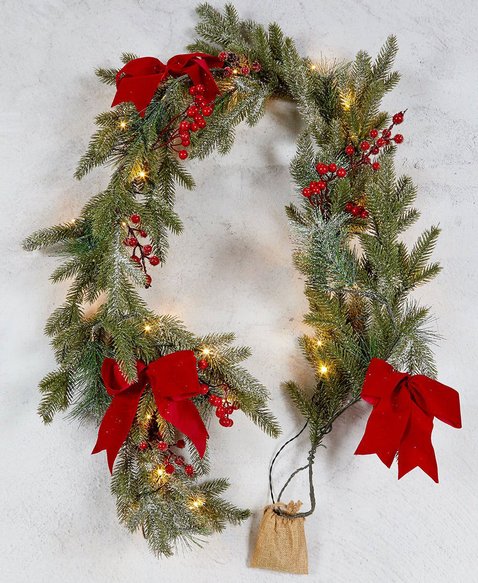Cozy family room fireplace framed by heavy frosted snowy pine garland with red velvet ribbon