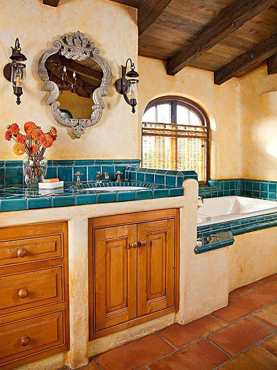 Southwestern powder room featuring unlacquered brass hardware, sand stucco walls, round mirror, warm sconce lighting.