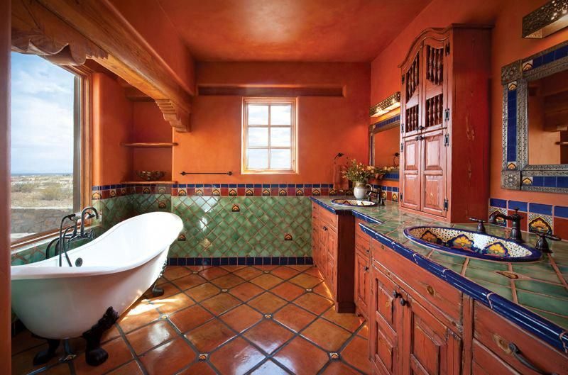 Southwestern bathroom with hand painted Talavera tile wall, wrought iron mirror, dark vanity, soft lighting.