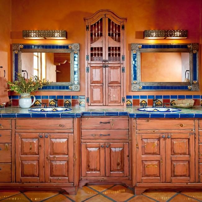 Southwestern style bathroom featuring warm terracotta tiles, carved wood vanity, copper sconces, clay plaster.