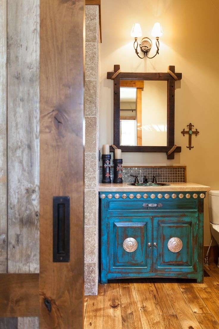 Southwestern style bathroom with blue Talavera tile, rustic pine vanity, antiqued brass mirror, warm light.
