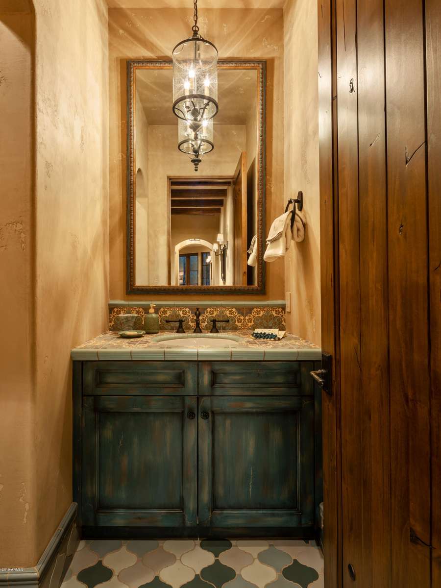Southwestern bathroom featuring freestanding copper soaking tub, exposed wooden ceiling vigas, travertine stone tiles, warm lighting.