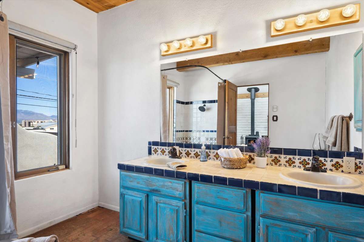 Southwestern bathroom with turquoise zellige tile shower, river rock floor, teak bench, soft vanity lighting.