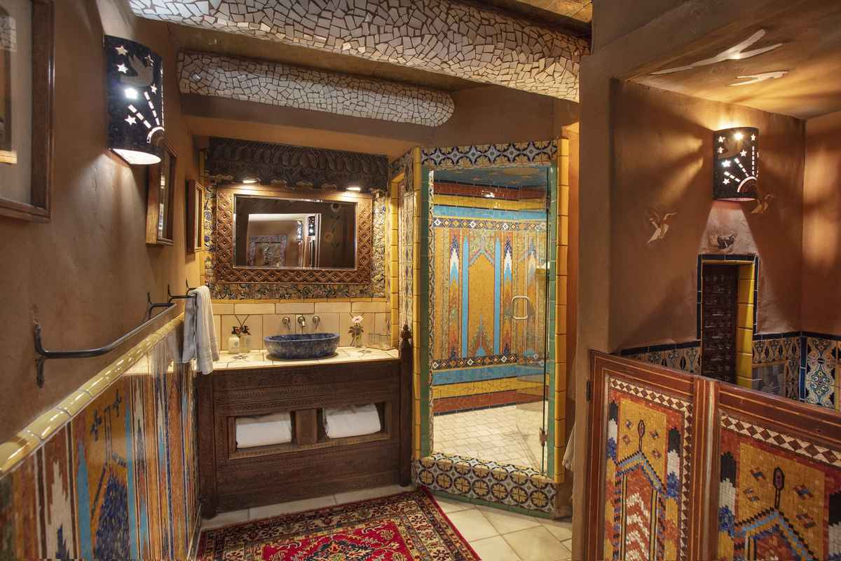 Moody southwestern bathroom featuring dark charcoal plaster walls polished copper tub and warm incandescent sconce lighting