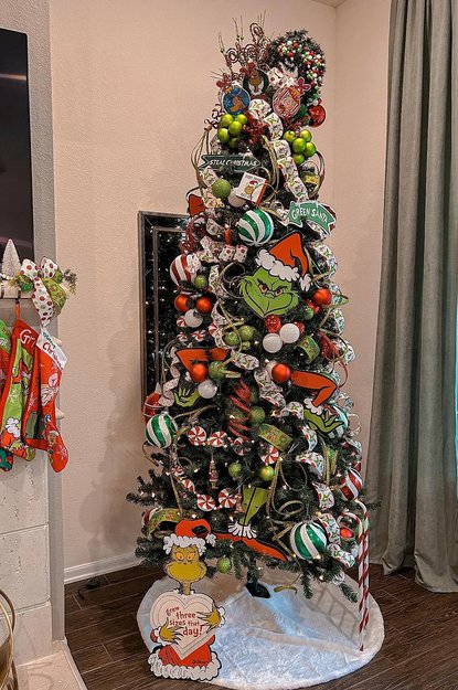 Tree with humorous steal christmas signs and green ornaments in a bright room
