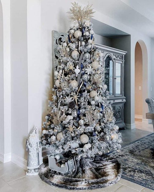 Transitional parlor highlighting striped ribbon garland tree near velvet chaise under brass chandelier