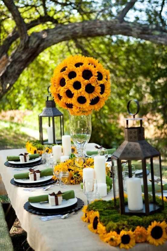 Outdoor table with sunflower lanterns, natural wood plates, soft amber lighting, garden backdrop