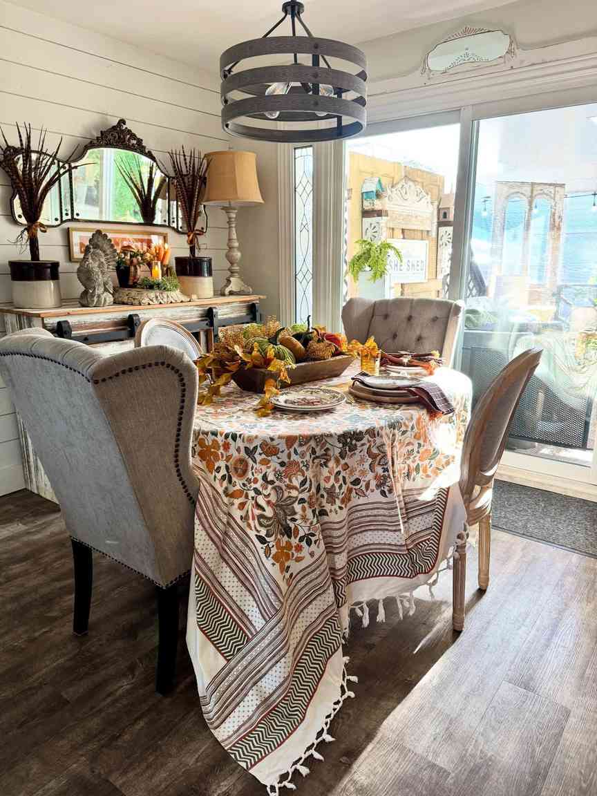 Bright dining room, floral tablecloth, white pumpkin centerpiece, natural wood table, daylight illumination.
