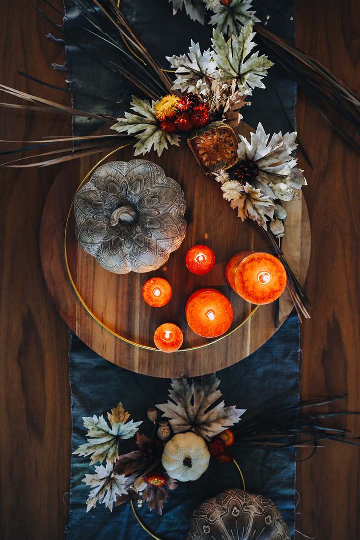 Low woven rattan tray filled with deep red pomegranates pinecones and seasonal greenery.