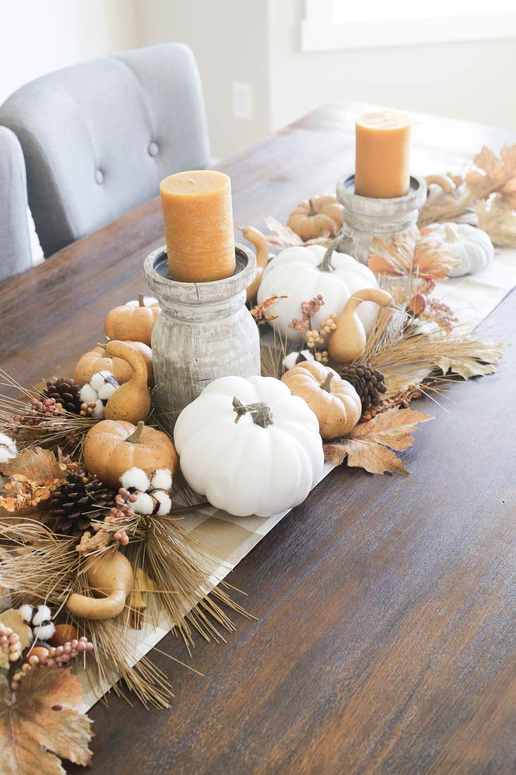 Terracotta pots with velvet accent pumpkins and burgundy dahlias on a dark table runner.