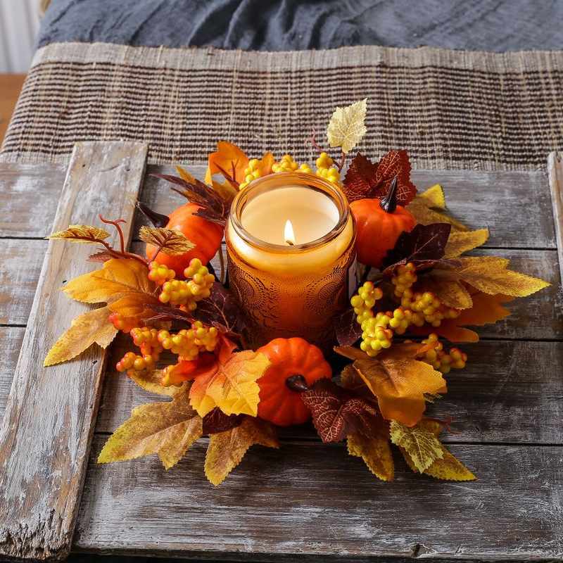 Tall bundled golden wheat sheaf tied with burlap ribbon surrounded by mini orange pumpkins.