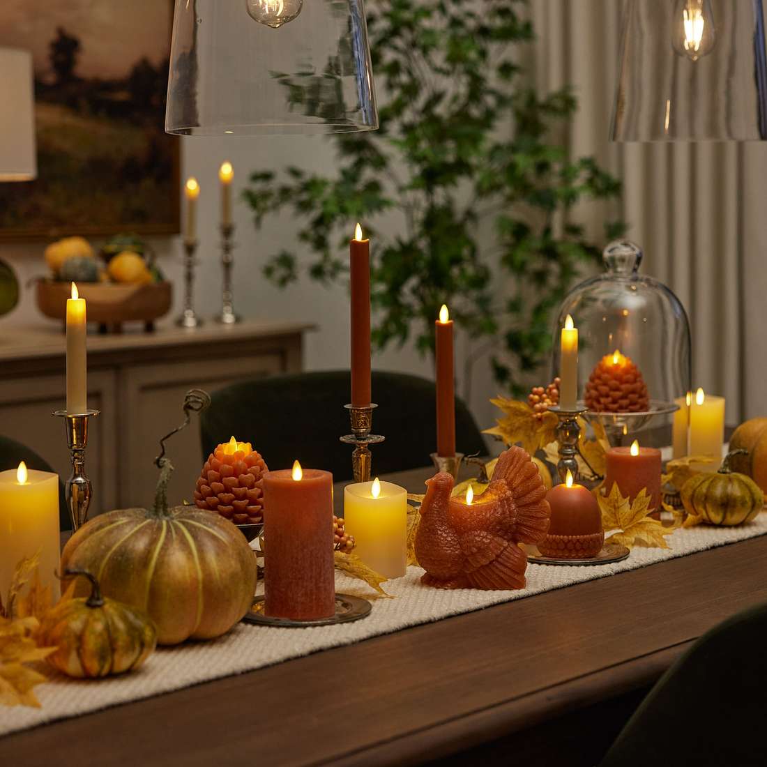 Warm copper lantern glowing amongst scattered red and orange maple leaves on wood table.