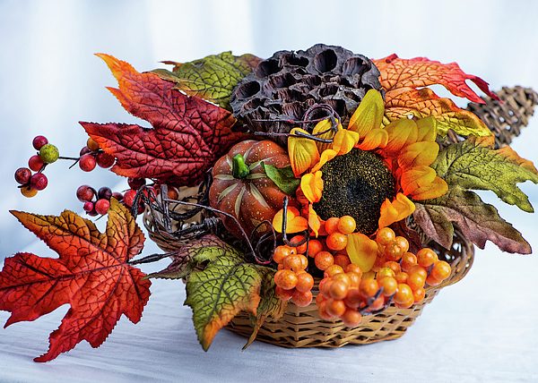 Metallic rose gold bowl filled with bright orange persimmons cream dahlias and eucalyptus.