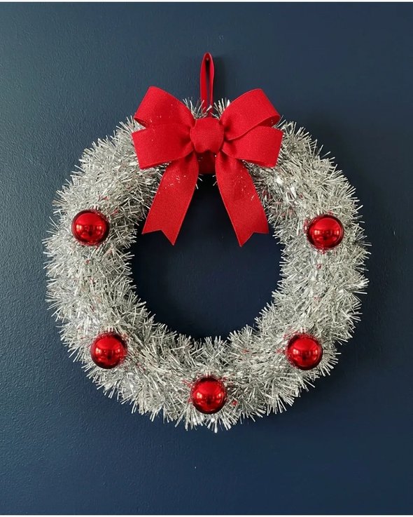 Shimmering tinsel wreath on white wall with bright lighting