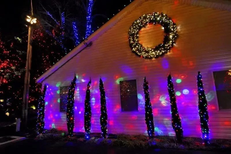 Unconcealed black plug connectors dangling visibly from a illuminated holiday wall garland display.