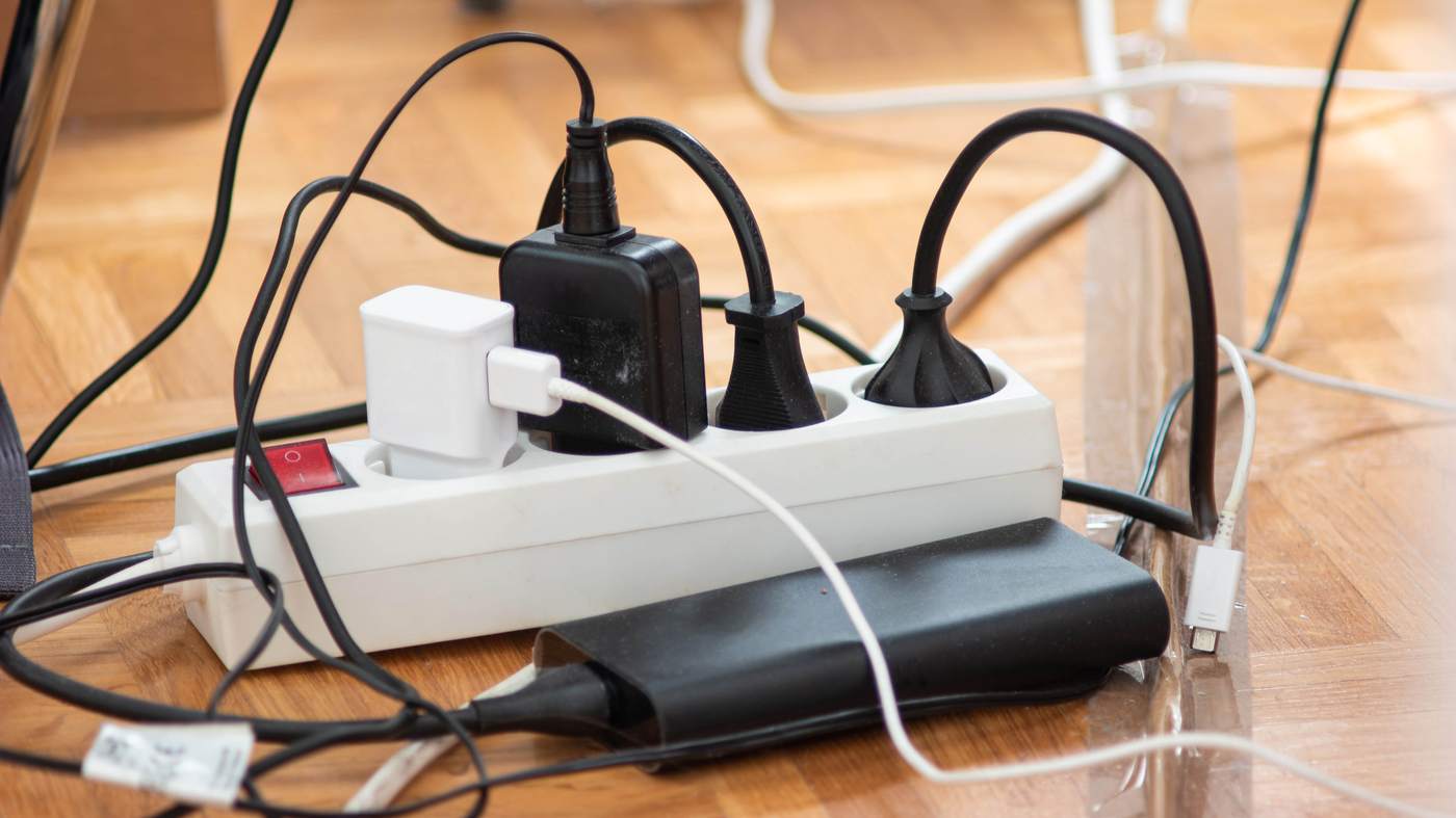 Fireplace hearth decor hiding an unsafe overloaded power strip crammed with multiple light plugs.