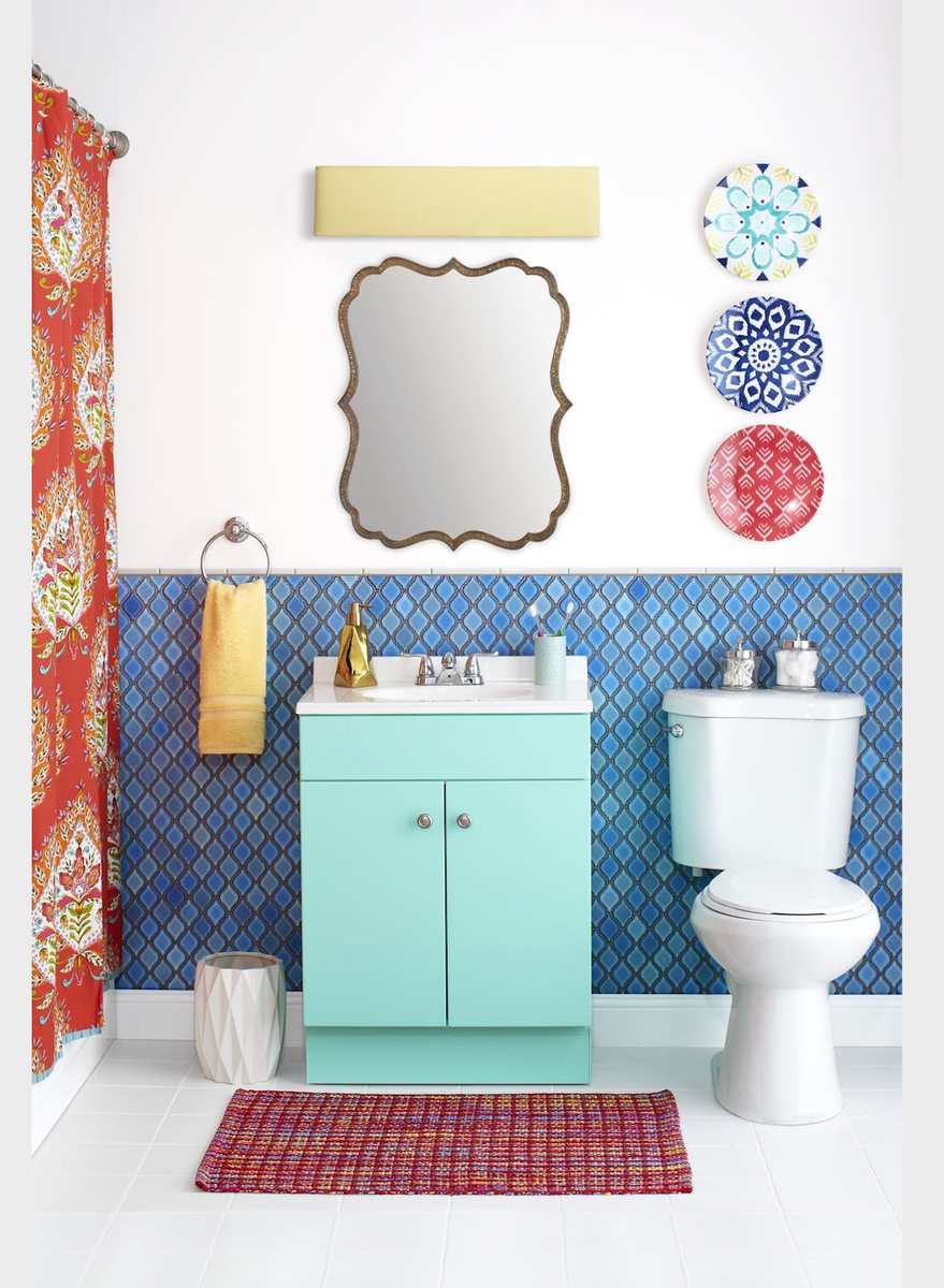 Bright turquoise bathroom vanity paired with colorful artwork, patterned rug, and gold accents.
