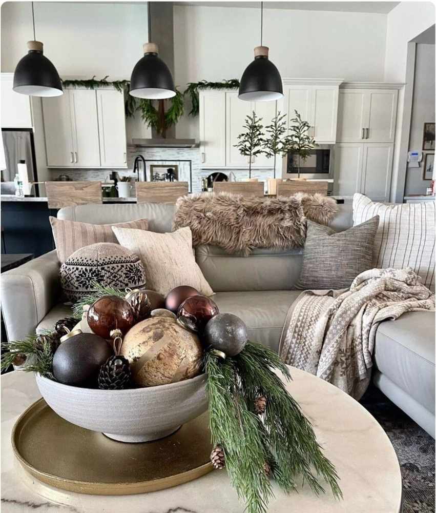 Vintage brass candle holders with tall ivory tapers and pine sprigs on a rustic coffee table.