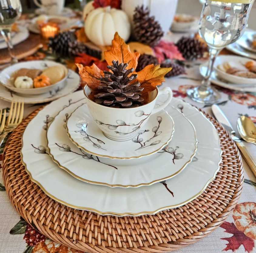 Classic dining, vintage pumpkin print chargers, ivory dinner plates, antique silverware, soft amber chandelier lighting