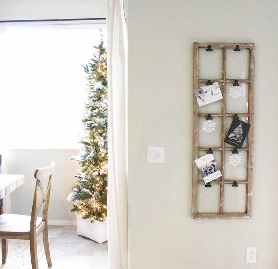 Distressed antique multi pane window frame mounted on wall holding holiday cards within glass grids