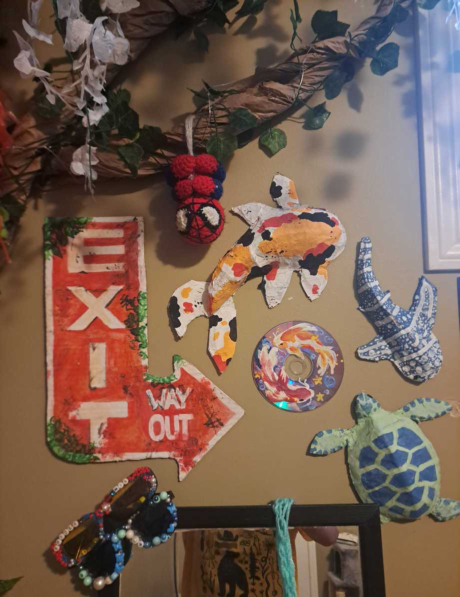 Colorful papier mache fish crafts hanging on a white wall in a coastal living room.
