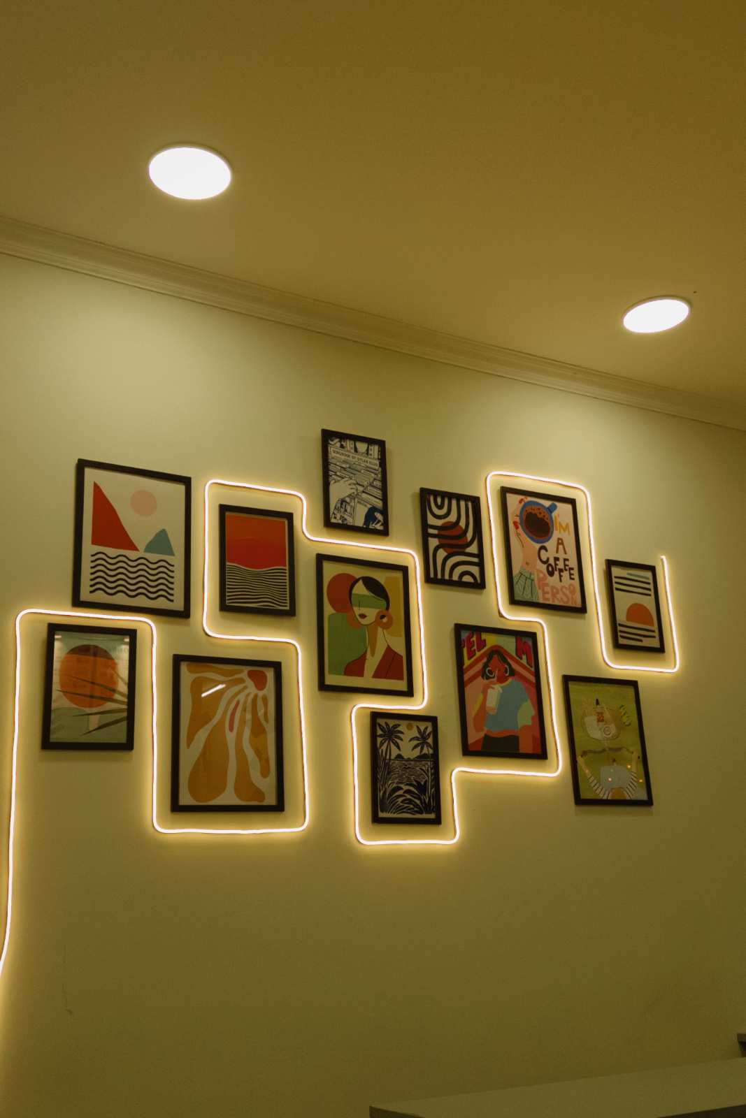 Gallery of framed art illuminated by colorful neon rope lights in a trendy loft.
