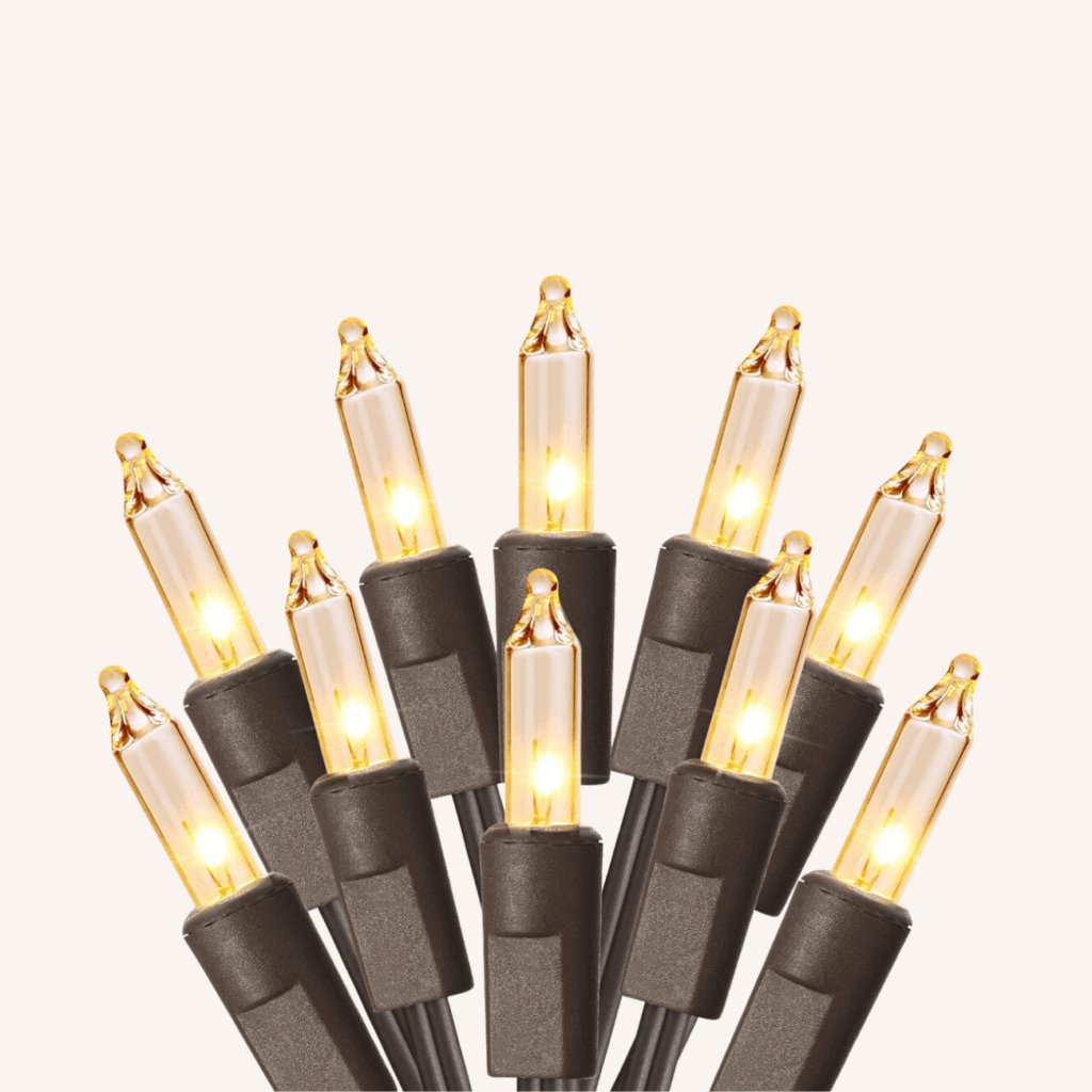Warm white mini lights wrapped around a delicate white oak tree branch in a minimalist ceramic vase.