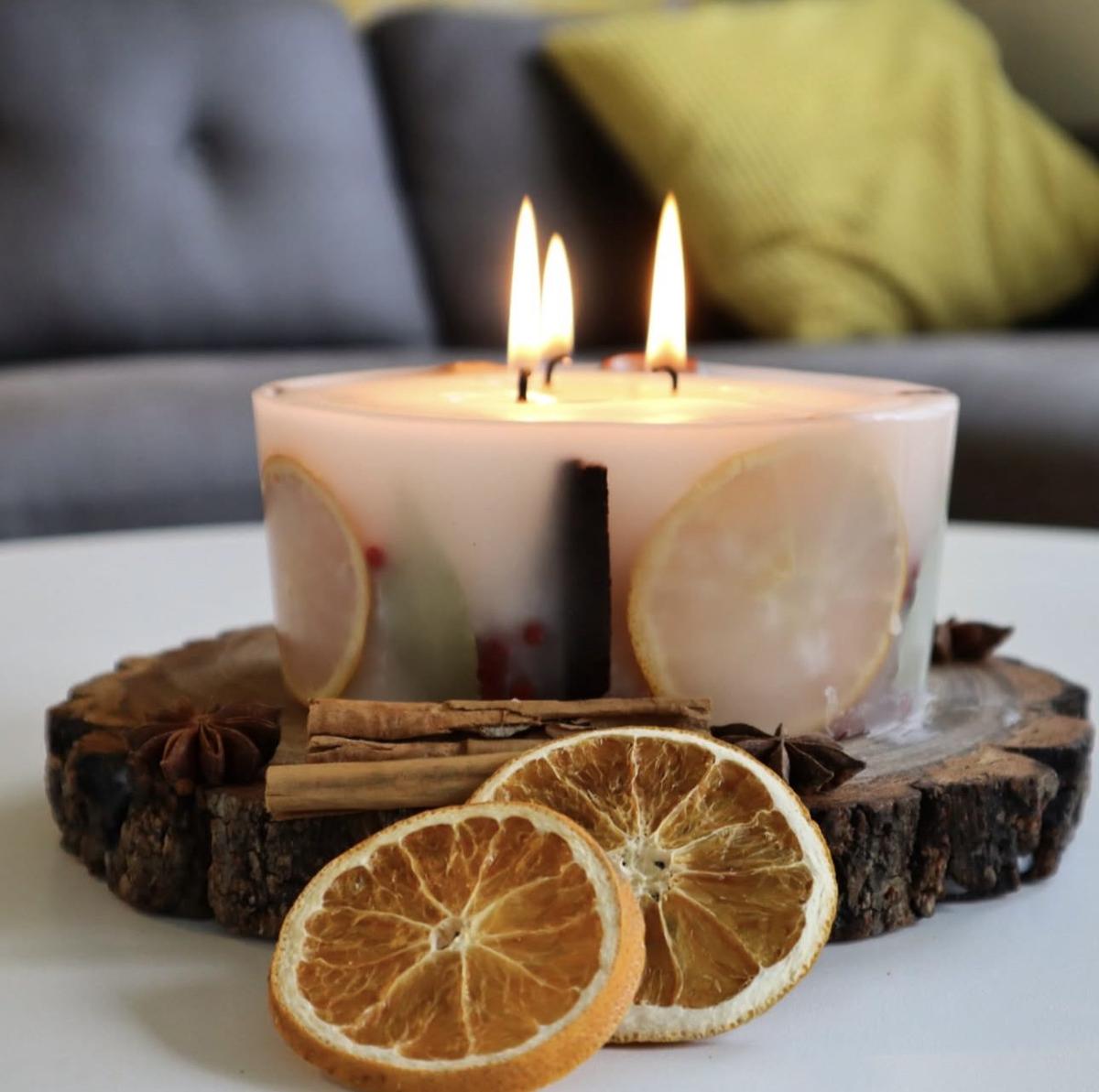 Warm wood coffee table decorated with wooden bowls, glowing glass candles, and subtle holiday greenery.