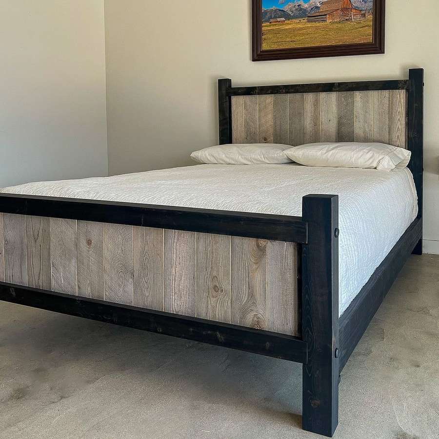 Rustic bedroom showcasing a weathered wood headboard, black metal bed frame, and charcoal bedding accents