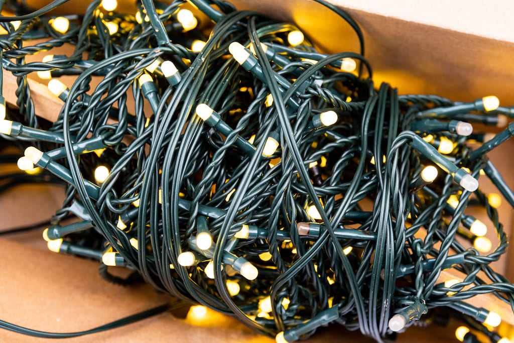 Decorator hanging christmas lights on a tree discovering half the strand is completely unlit.