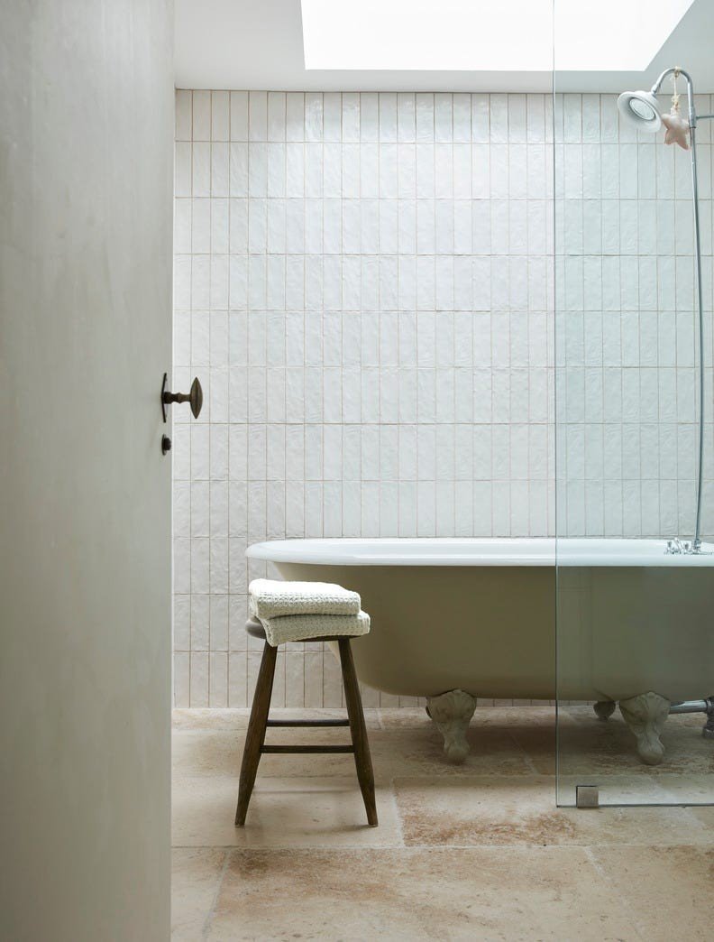 Modern white wet room bathroom featuring freestanding clawfoot tub, frameless glass enclosure, and recessed lighting