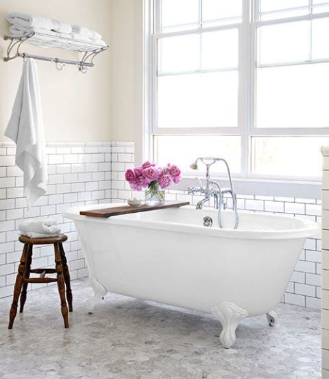 White bathroom design ideas featuring white clawfoot tub, soft pink floral arrangements, and natural sunlight