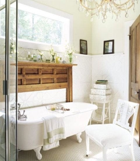 Modern white bathroom featuring clawfoot tub, white oak vanity, ceramic tiles, and warm wall sconces