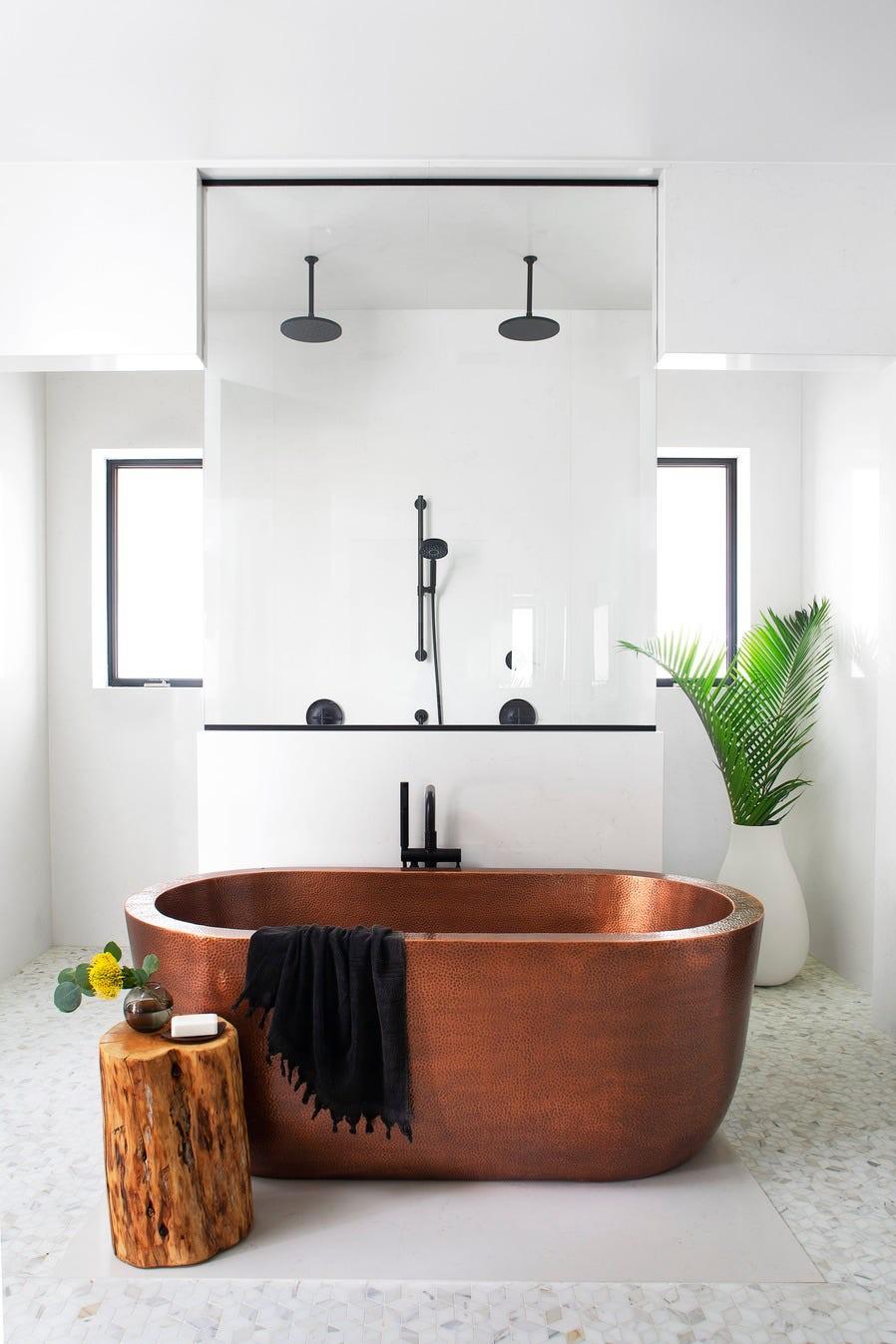Spa bathroom design featuring copper soaking tub, ceiling rain shower head, white marble, and natural light