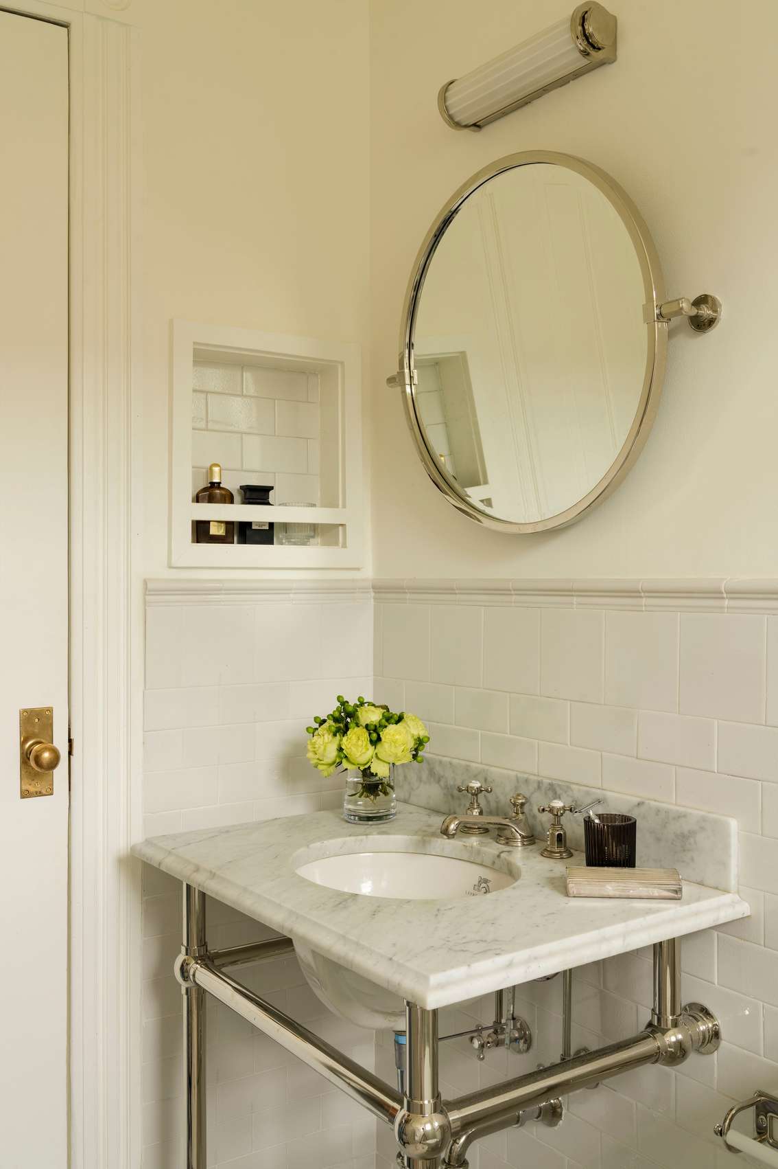 Vintage white bathroom featuring marble console sink, brass leg supports, subway tile wainscot, and mirror