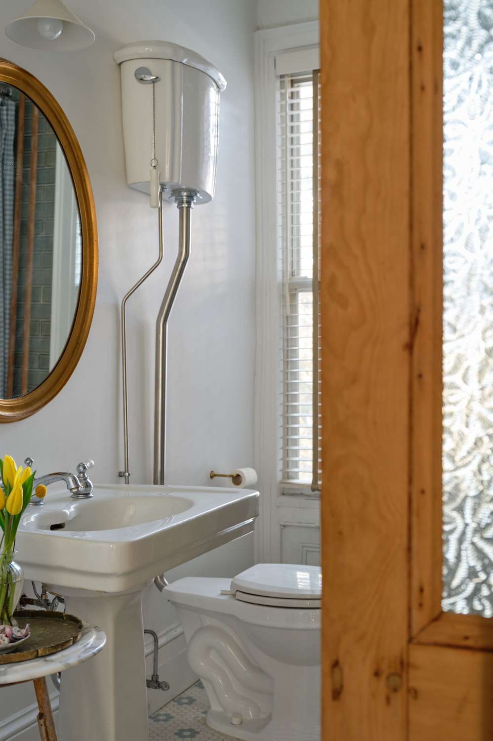 Elegant white bathroom design ideas featuring a porcelain pedestal sink paired with an ornate gold mirror.