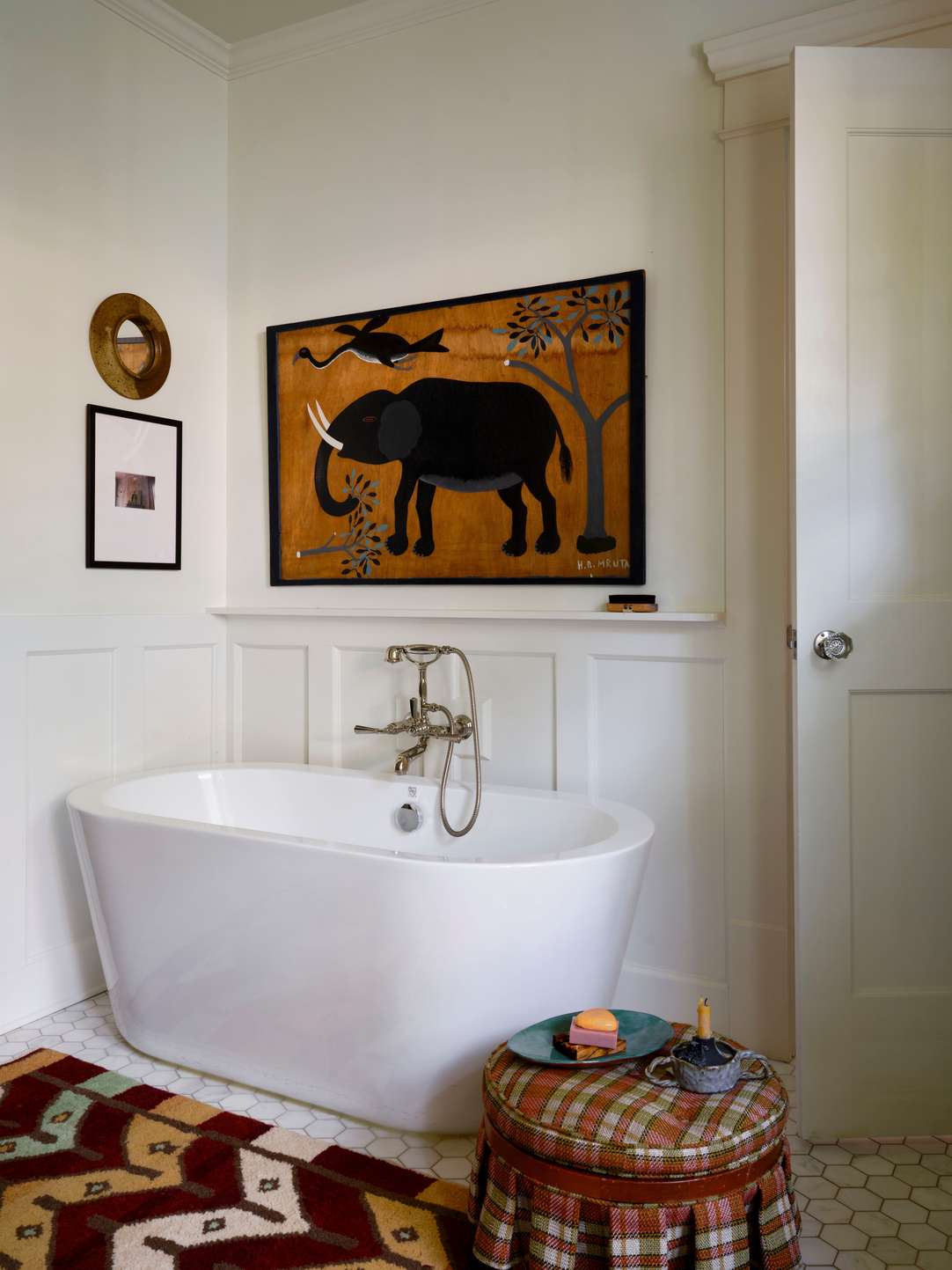 Creative white bathroom design ideas featuring a white bathtub beneath a large framed black and white elephant print.