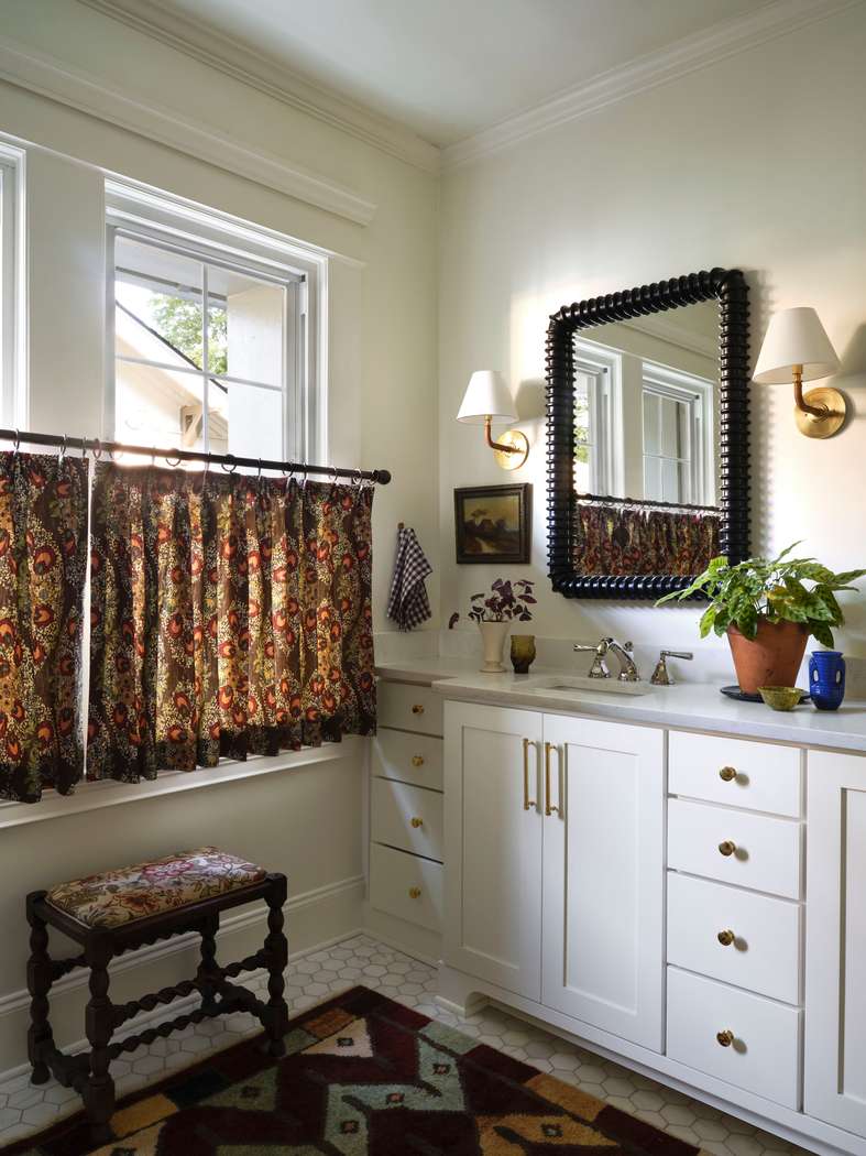 Cottage white bathroom design ideas featuring a white vanity with a charming floral fabric curtain skirt.