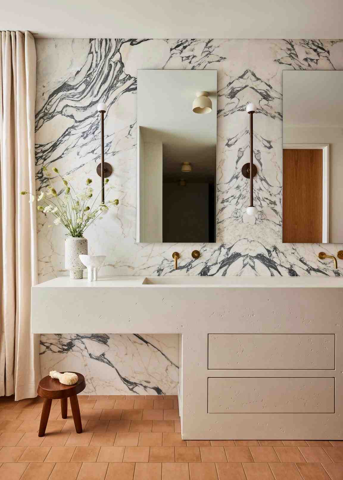 Modern luxury white bathroom design ideas featuring a floating white vanity on a dramatic white marble wall.