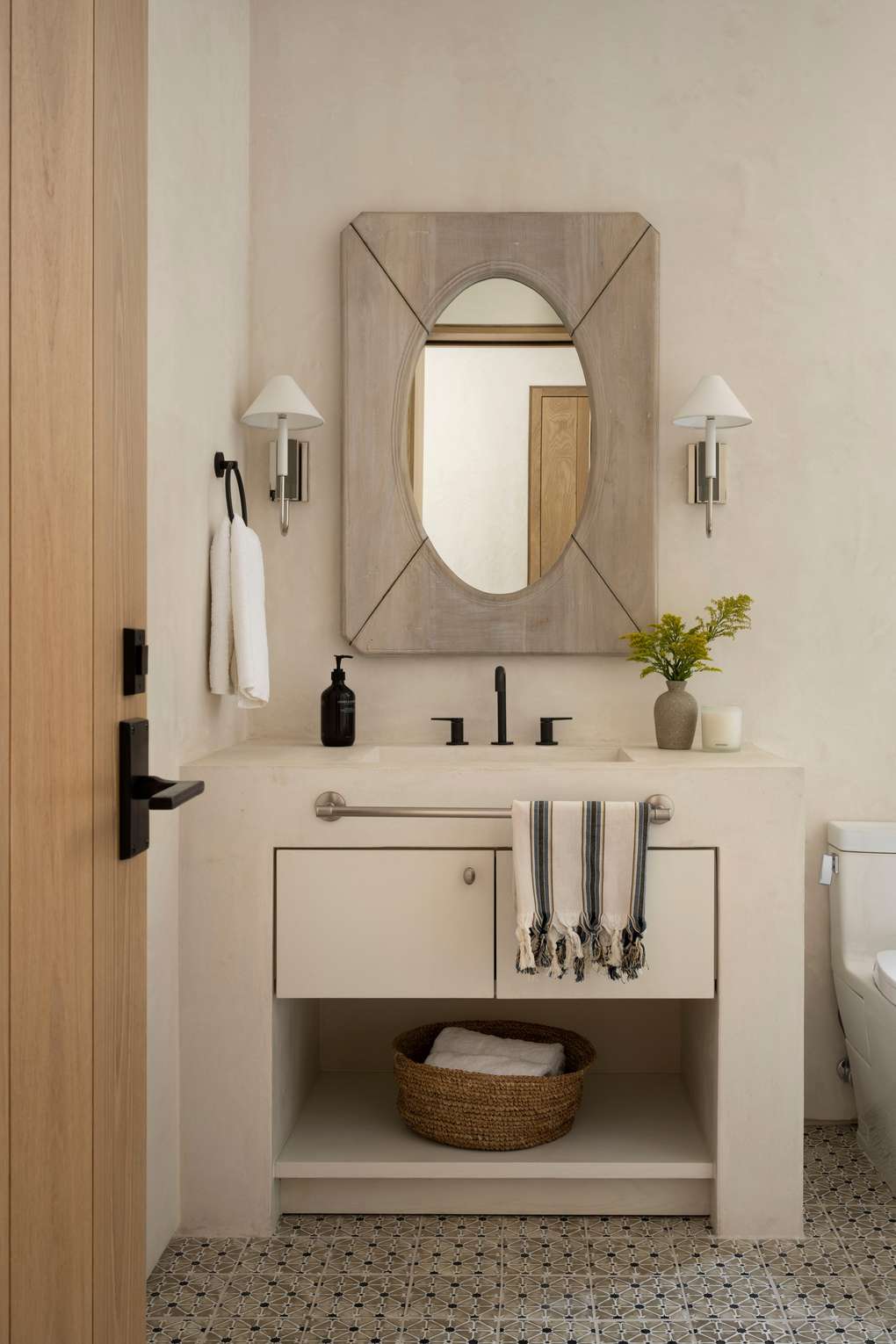 Timeless white bathroom design ideas displaying a white shaker vanity with a brass-rimmed oval mirror above.