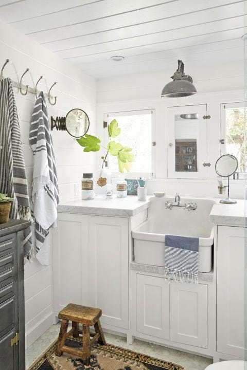 Practical white bathroom design ideas featuring matte black towel hooks mounted beside a white vanity setup.