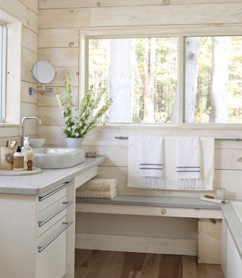 Bright white bathroom design ideas displaying a white vessel sink vanity positioned under a sunlit window.