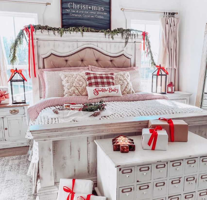 White bed with garland and wrapped gifts, festive lighting, and clean decor.