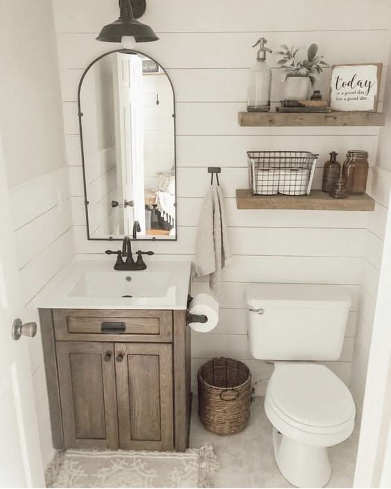 Farmhouse bathroom featuring white shiplap walls, a reclaimed wood vanity, black farmhouse sink, and vintage lantern lighting.