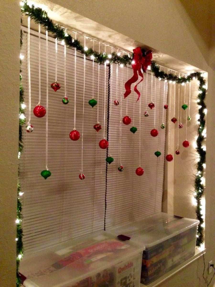 Window sill displaying a line of glass Christmas ornaments, pinecones, and tiny evergreen sprigs, illuminated by morning sunlight.