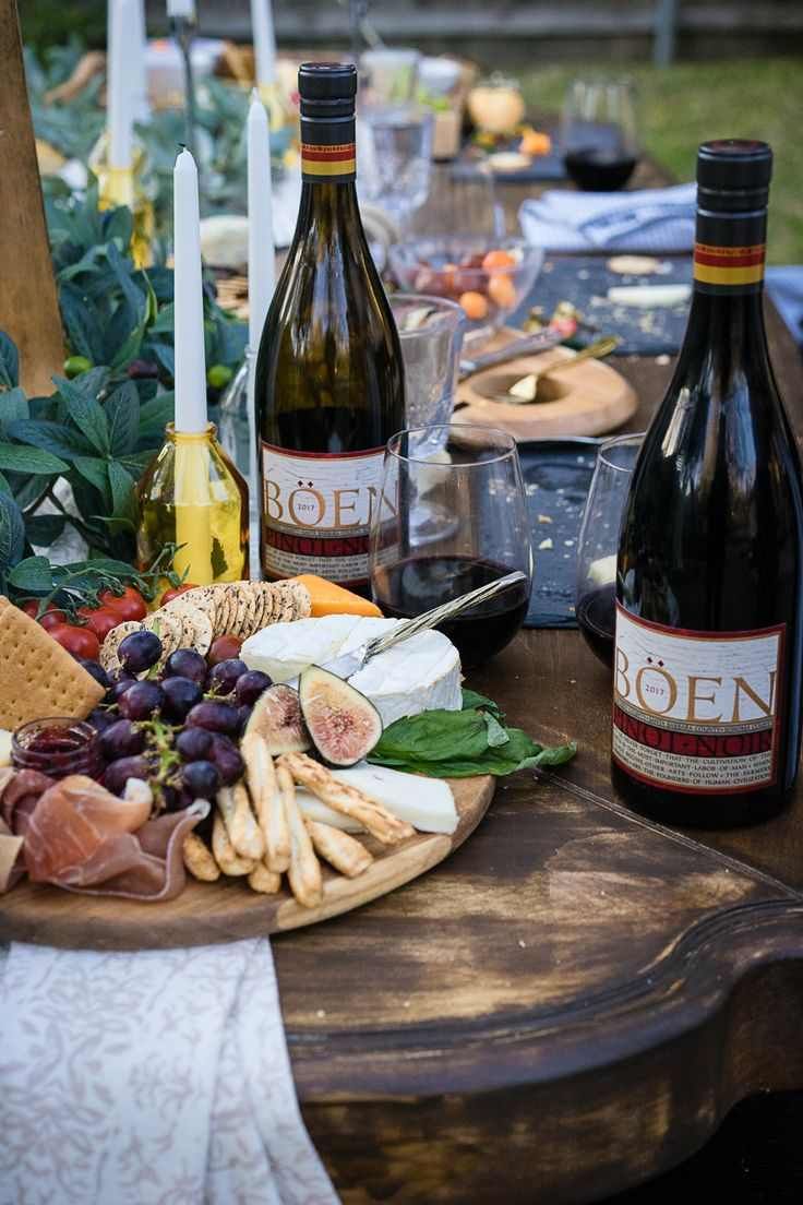 Large wooden grazing board with assorted cheeses, cured meats, grapes, nuts, soft ambient lighting, elegant setting