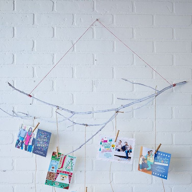 Suspended natural birch tree branch with hanging ribbons holding cards in modern minimalist dining room