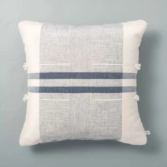 A cozy wool throw pillow with neutral stripes resting on a sofa