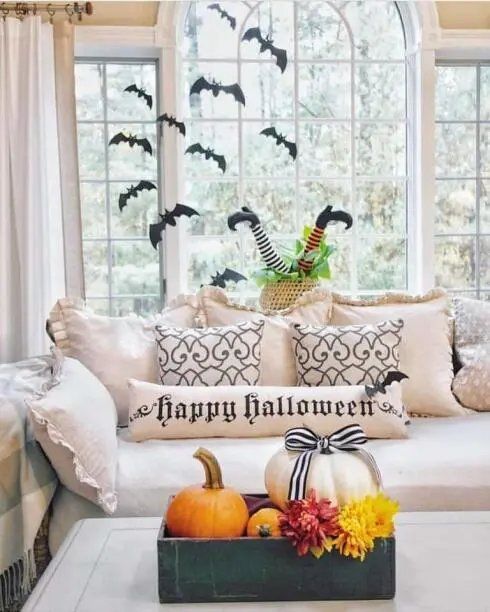 Living room sofa with witch leg props, window decals of bats, and dark curtains.