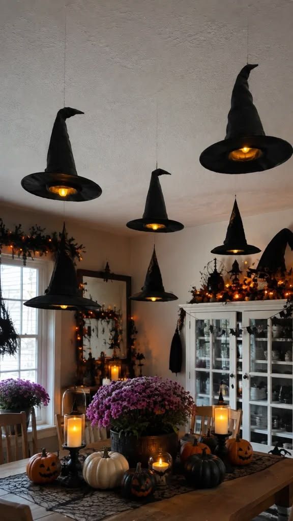 Illuminated floating witch hats over a dining table with dark tablecloth.